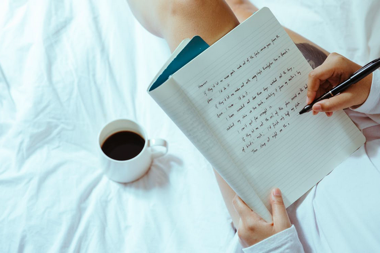 woman writing in journal with cup of coffee as a success habit