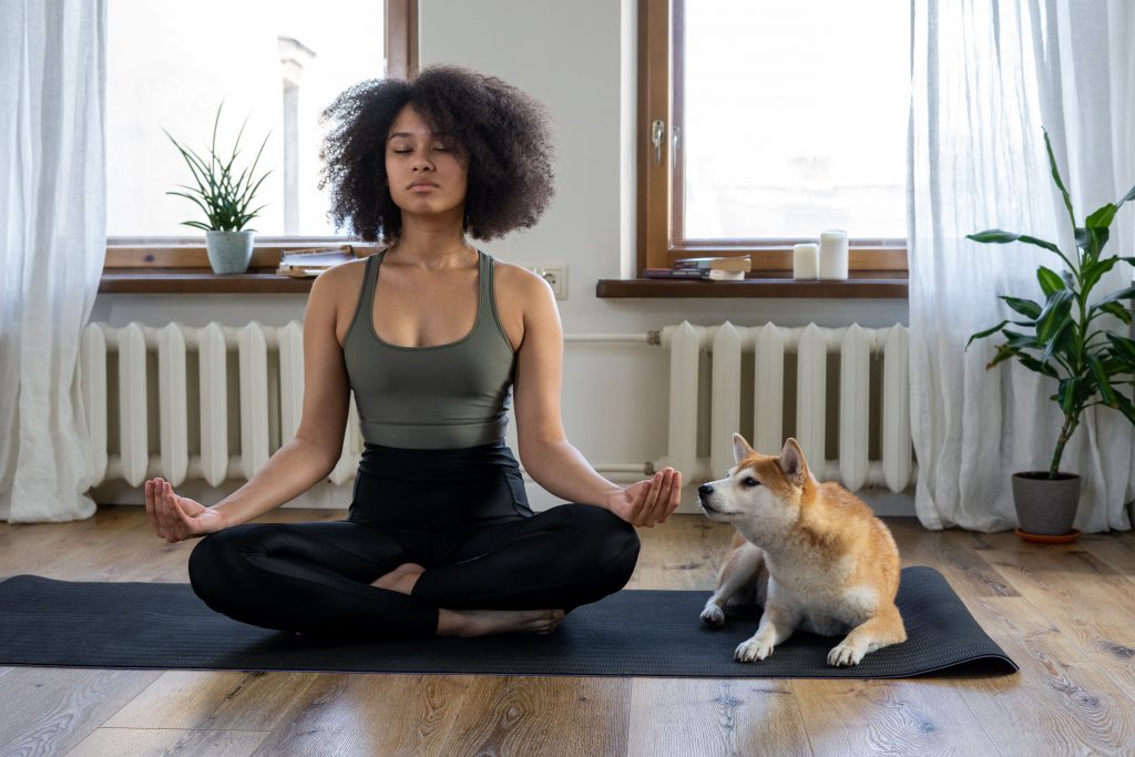 woman doing yoga with dog trying to stay motivated