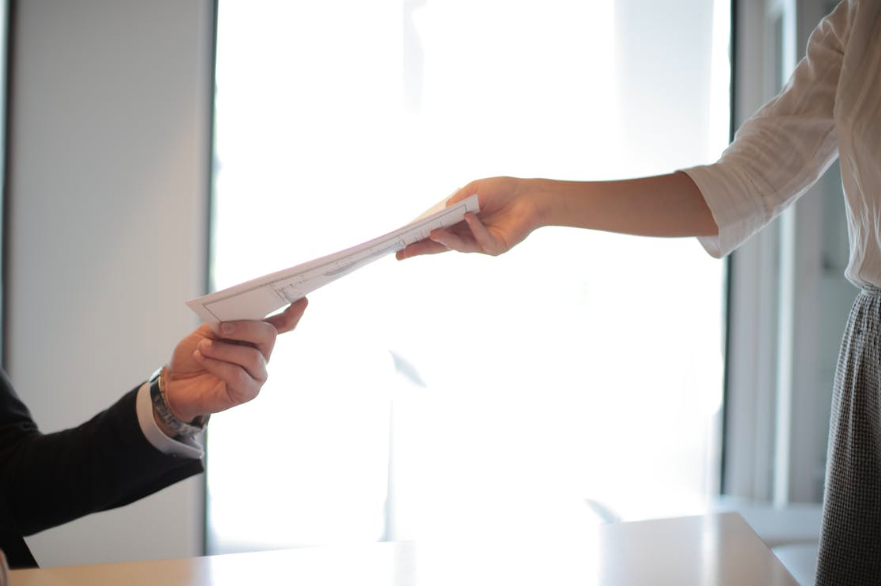 photo of woman handing man piece of paper