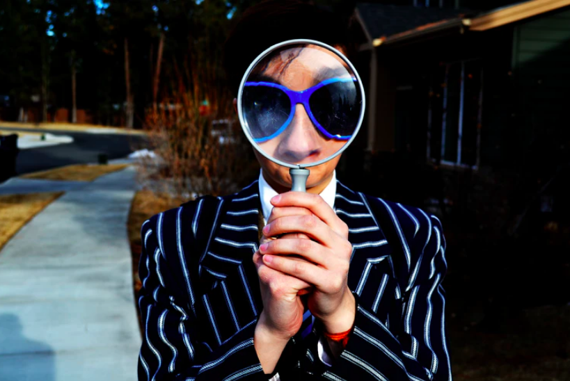 photo of woman holding magnifying glass to her face