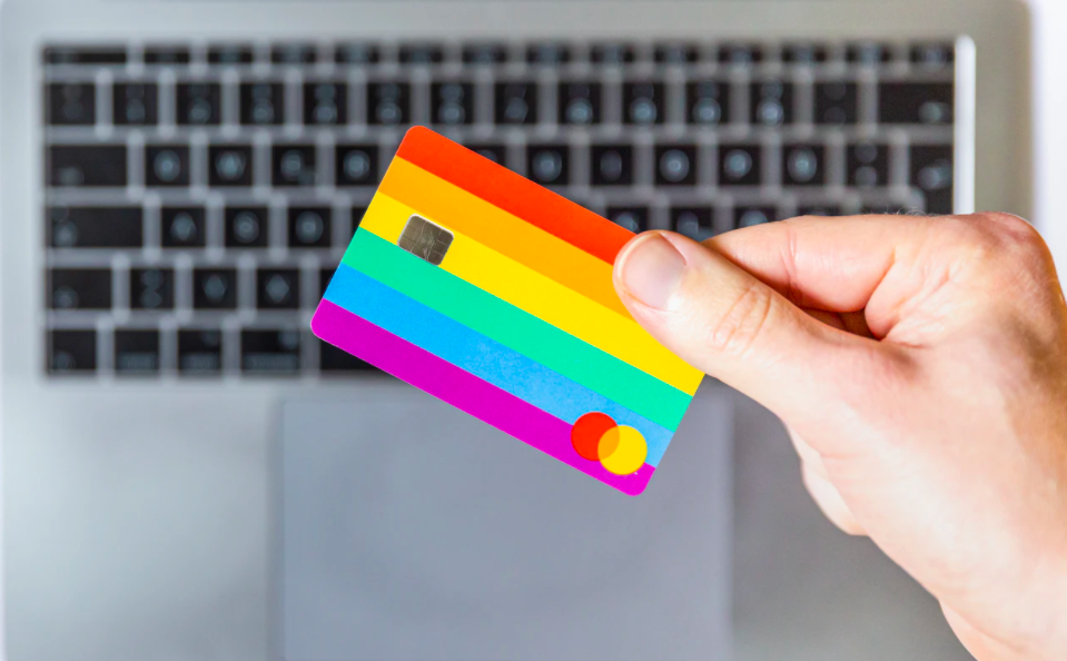 hand holding rainbow credit card over computer
